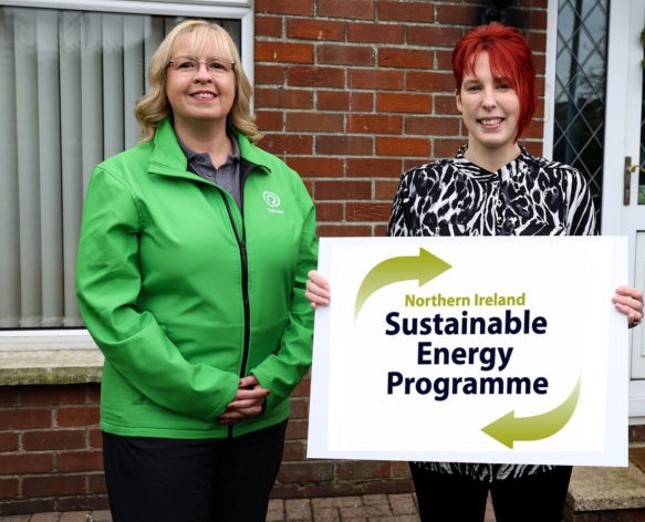 Pippa from Refresh NI and Customer holding Northern Ireland Sustainable Energy Programme Sign