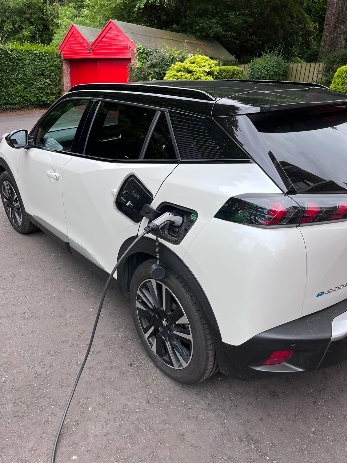 A white Electric Vehicle plugged in charging at a property