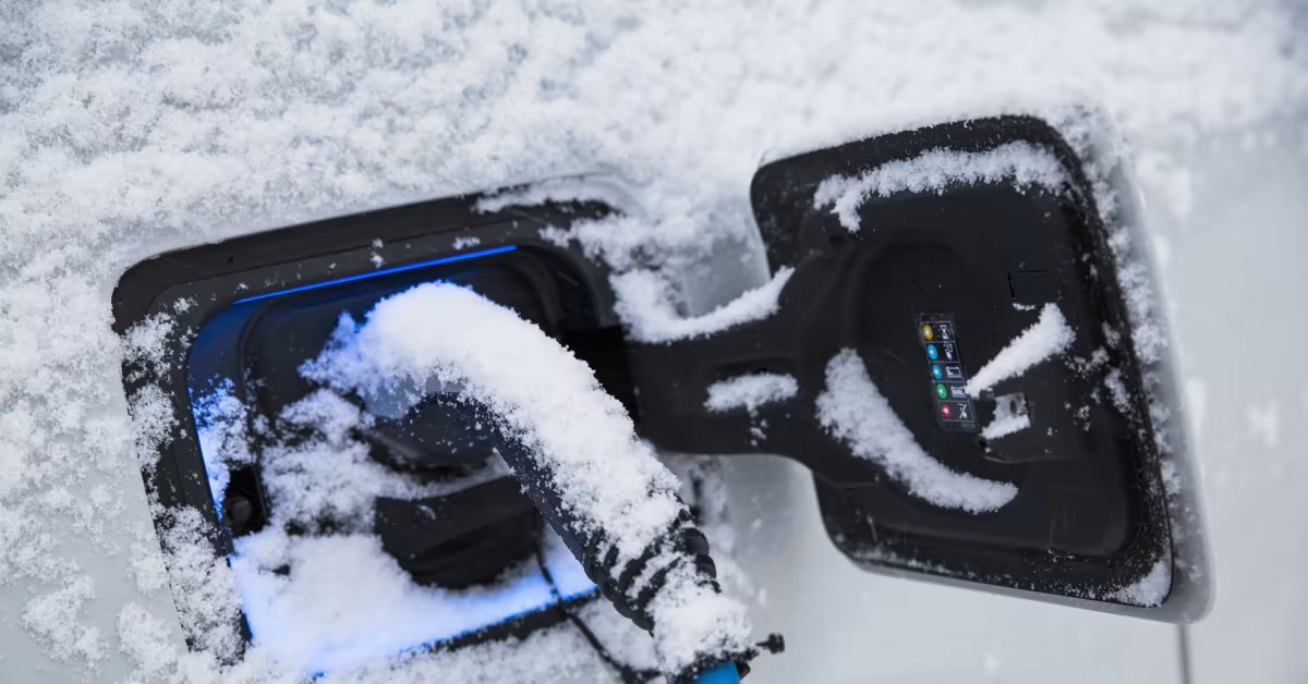 Electric Vehicle plugged in charging covered in snow.