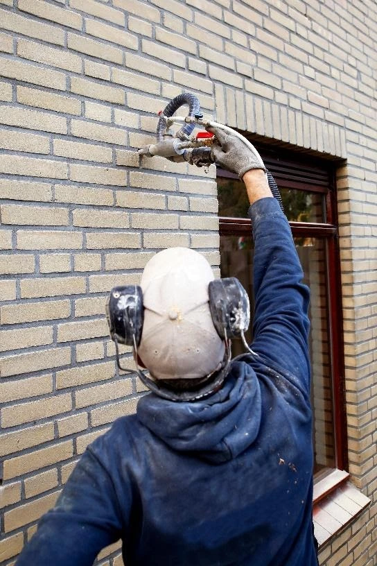 Engineer installing Cavity Wall Insulation outside a property